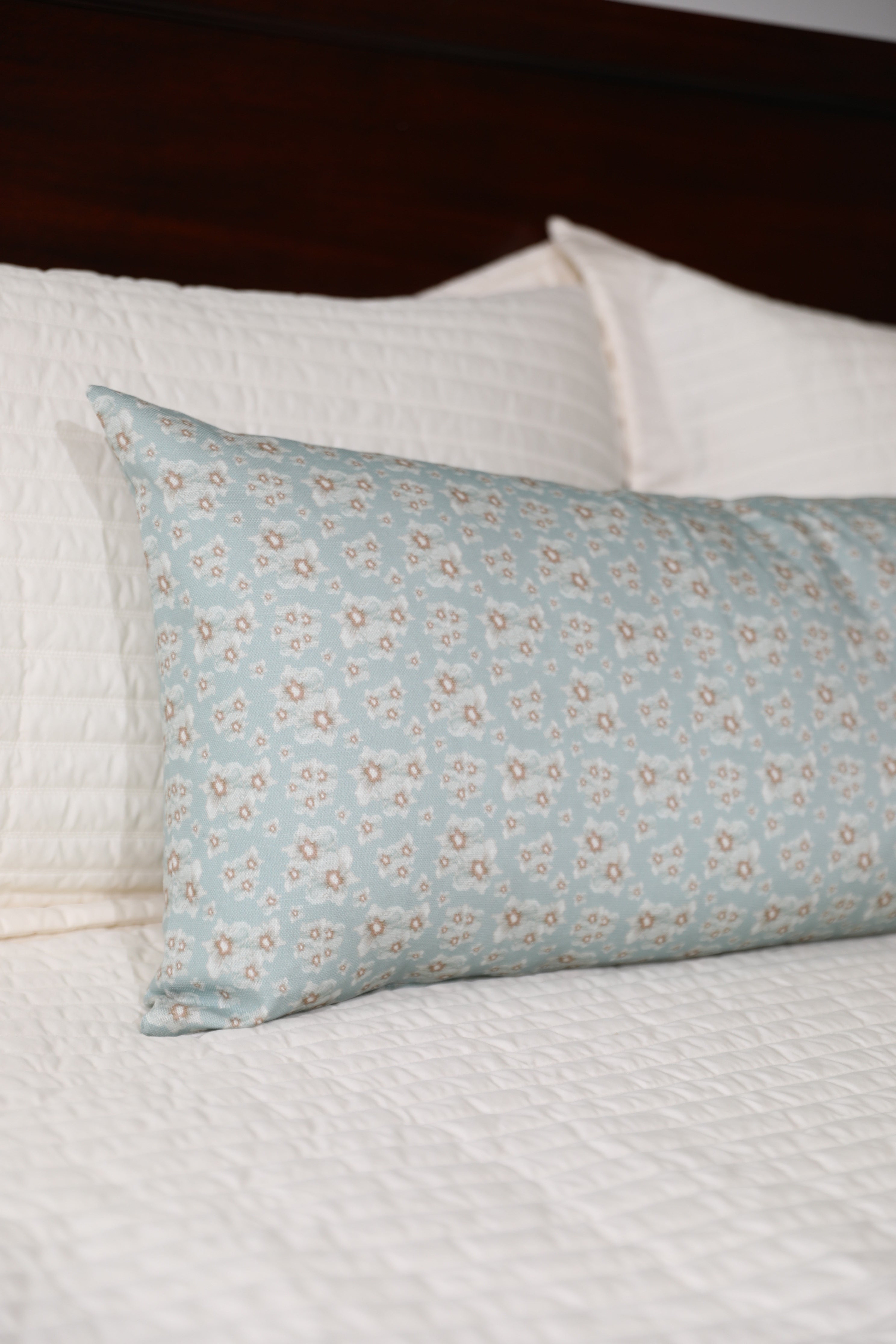 Luxury floral bolster pillow featuring a delicate cottage garden pattern with soft botanical detail, handcrafted in England for timeless and layered interiors.