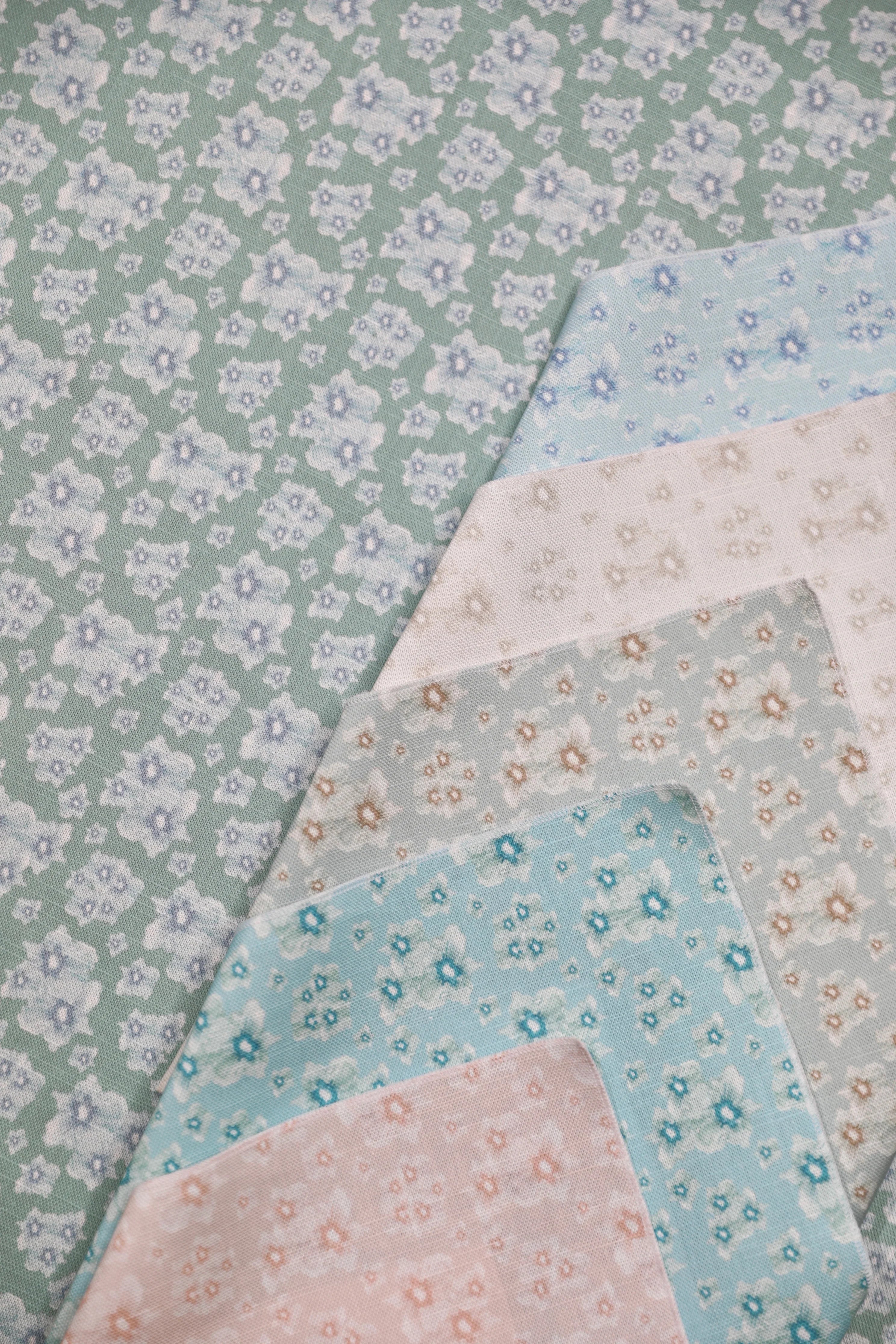 Set of floral fabric swatches in pastel colors on a green background