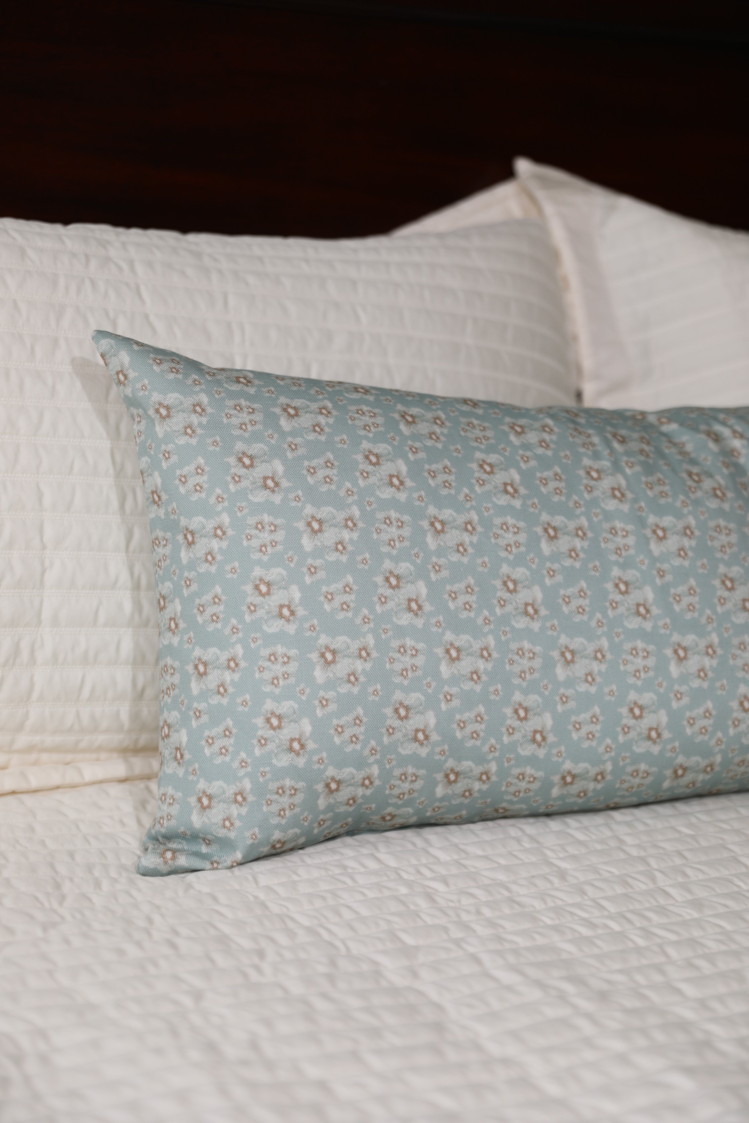 Luxury floral bolster pillow featuring a delicate cottage garden pattern with soft botanical detail, handcrafted in England for timeless and layered interiors.