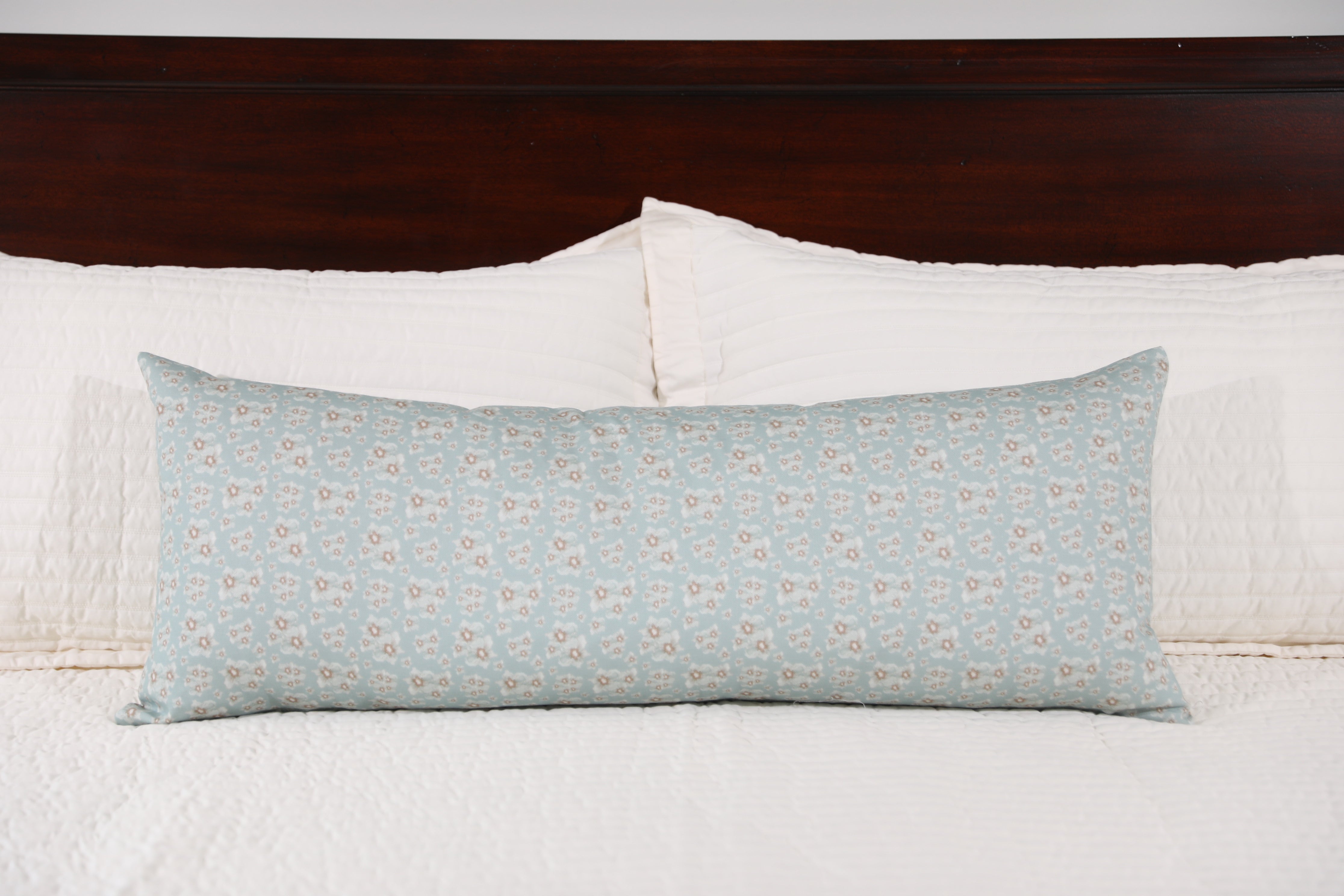 Luxury floral bolster pillow featuring a delicate cottage garden pattern with soft botanical detail, handcrafted in England for timeless and layered interiors.