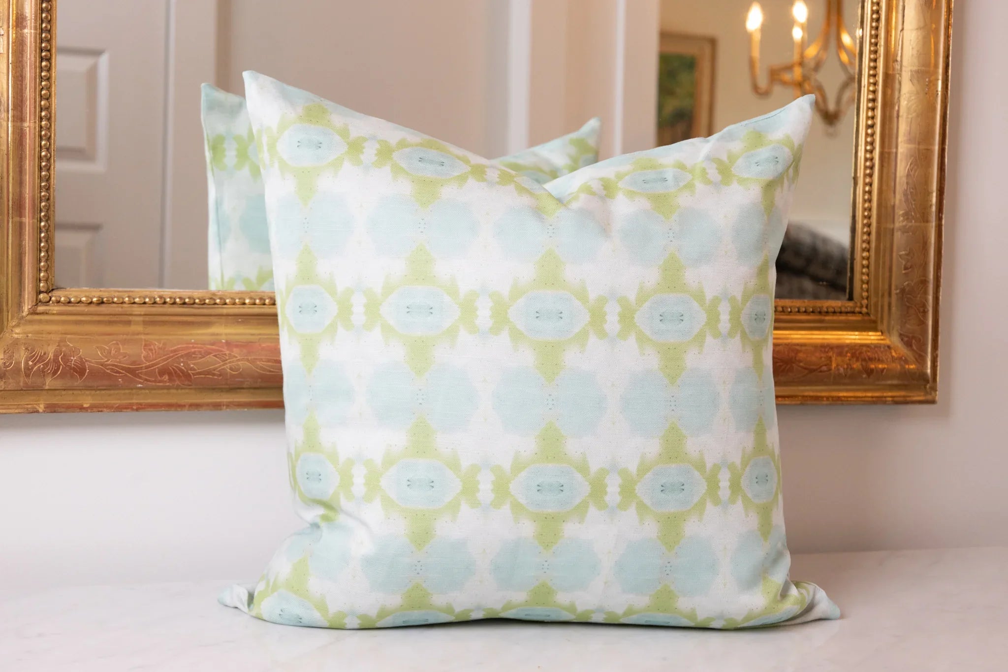 Luxury decorative pillow featuring an abstract small repeat pattern in chartreuse green and soft blue tones, styled for a layered modern traditional interior.