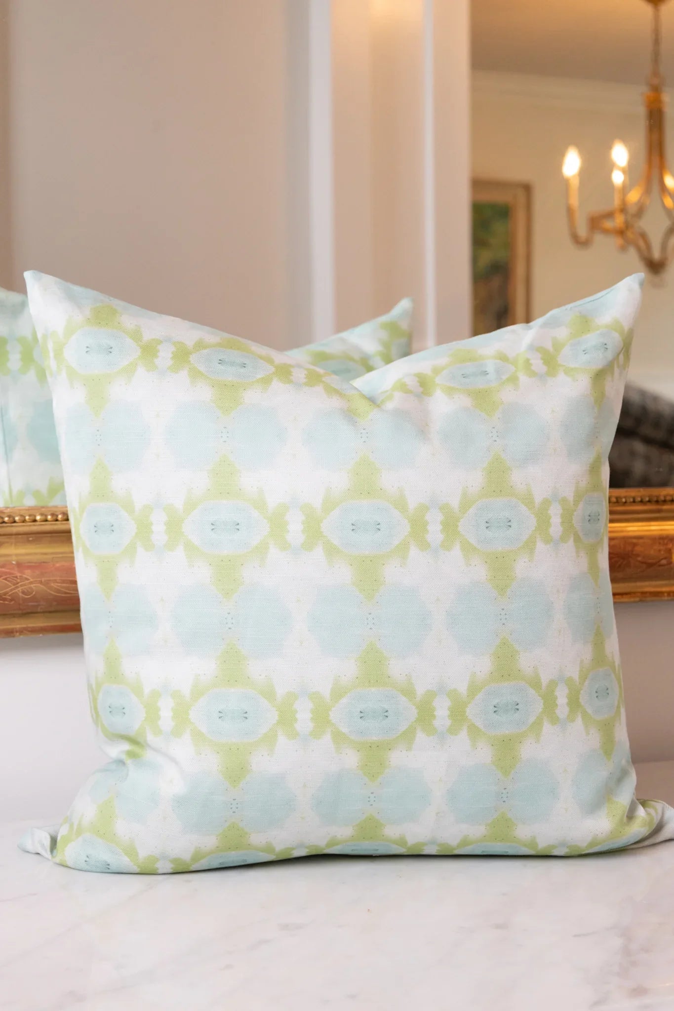 Luxury decorative pillow featuring an abstract small repeat pattern in chartreuse green and soft blue tones, styled for a layered modern traditional interior.