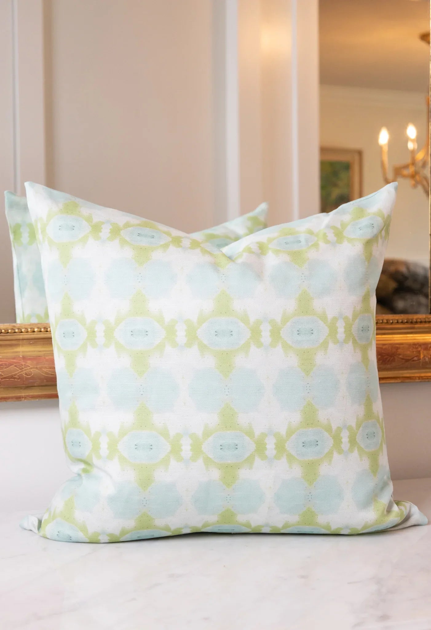 Luxury decorative pillow featuring an abstract small repeat pattern in chartreuse green and soft blue tones, styled for a layered modern traditional interior.