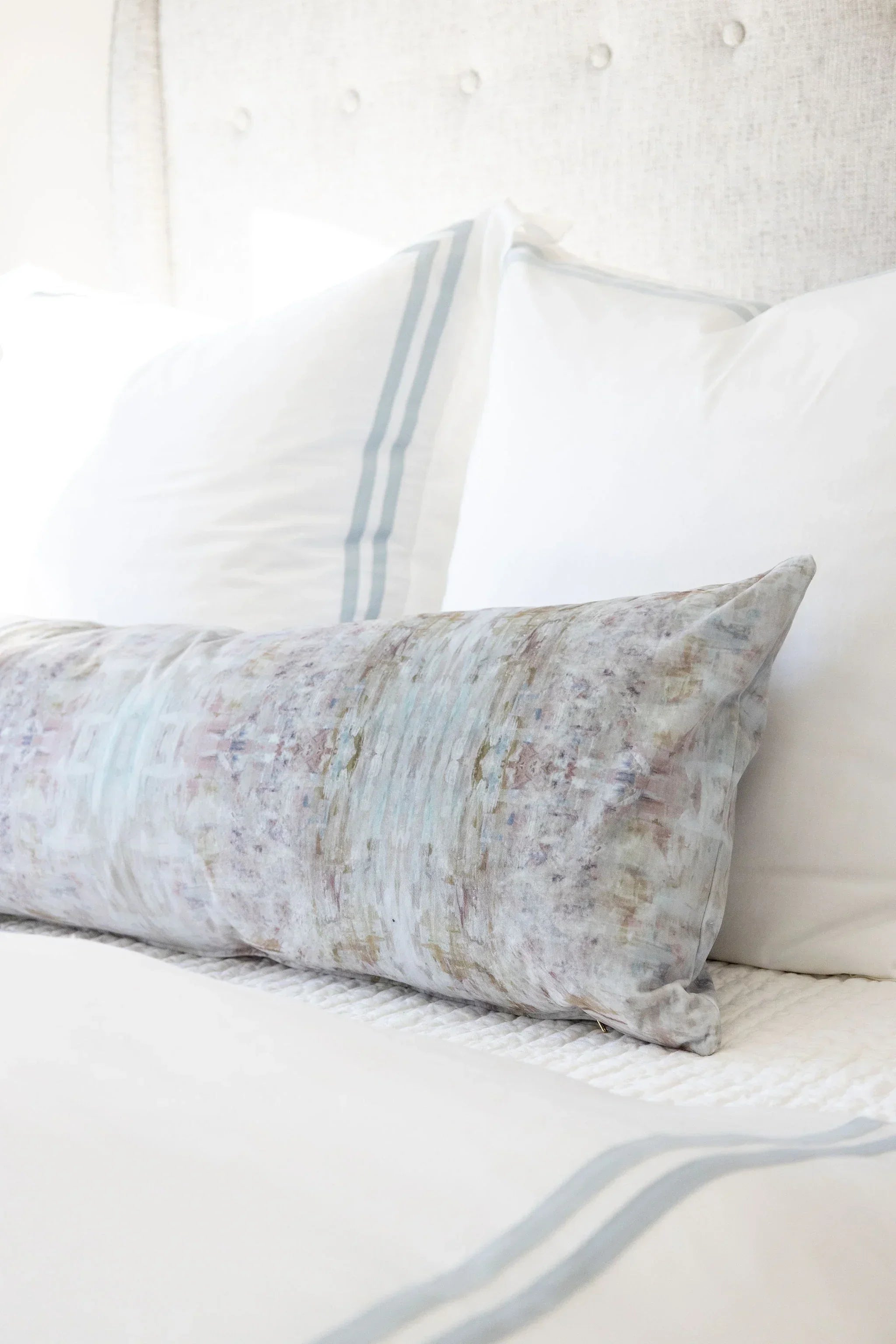 Luxury bolster pillow featuring an abstract garden-inspired pattern in layered bronze, iris blue, and earthy tones, styled for a collected modern traditional interior.