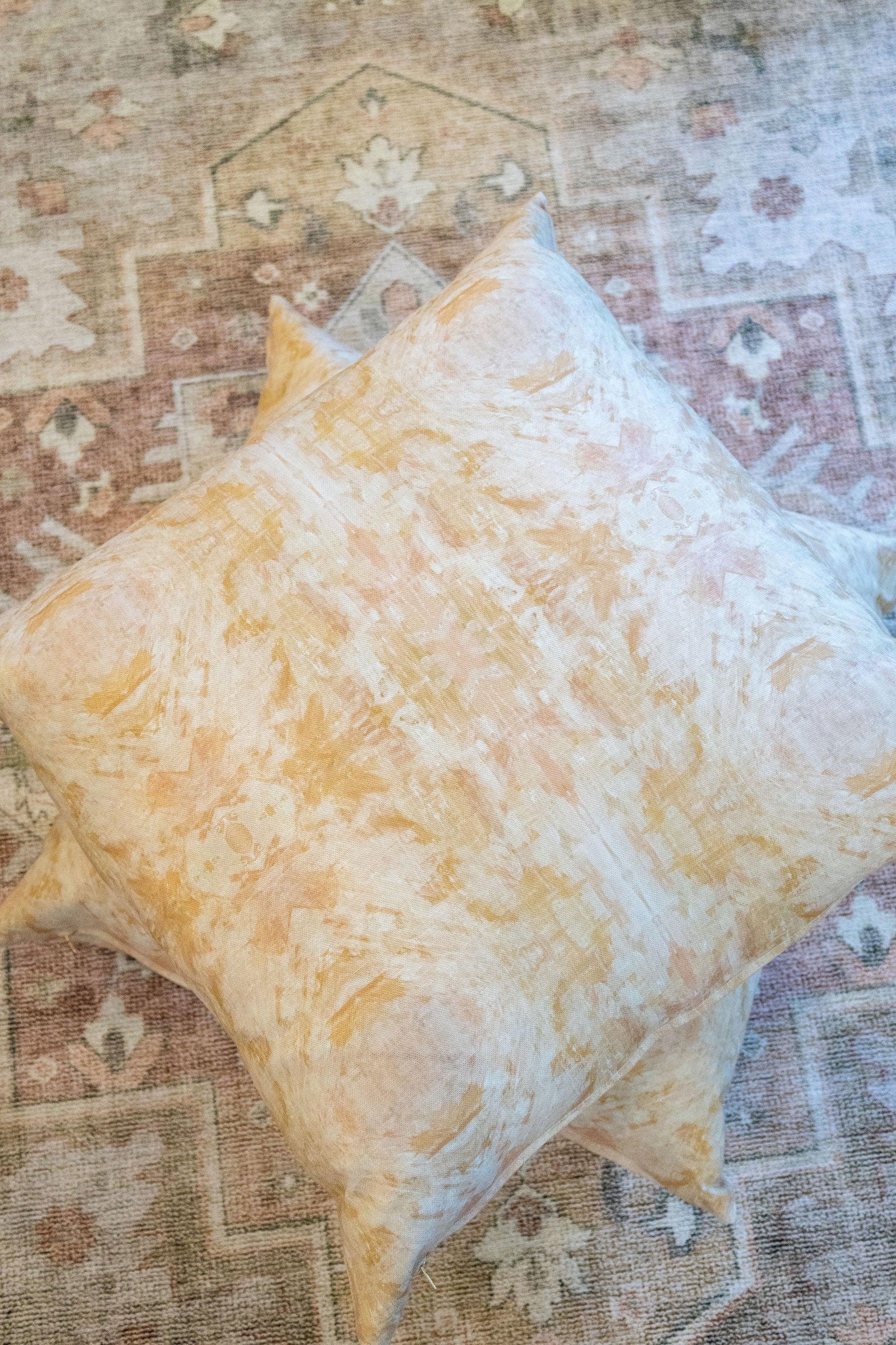Luxury decorative pillow featuring an abstract topiary-inspired pattern in warm autumn gold and neutral tones, styled for a layered modern traditional interior.