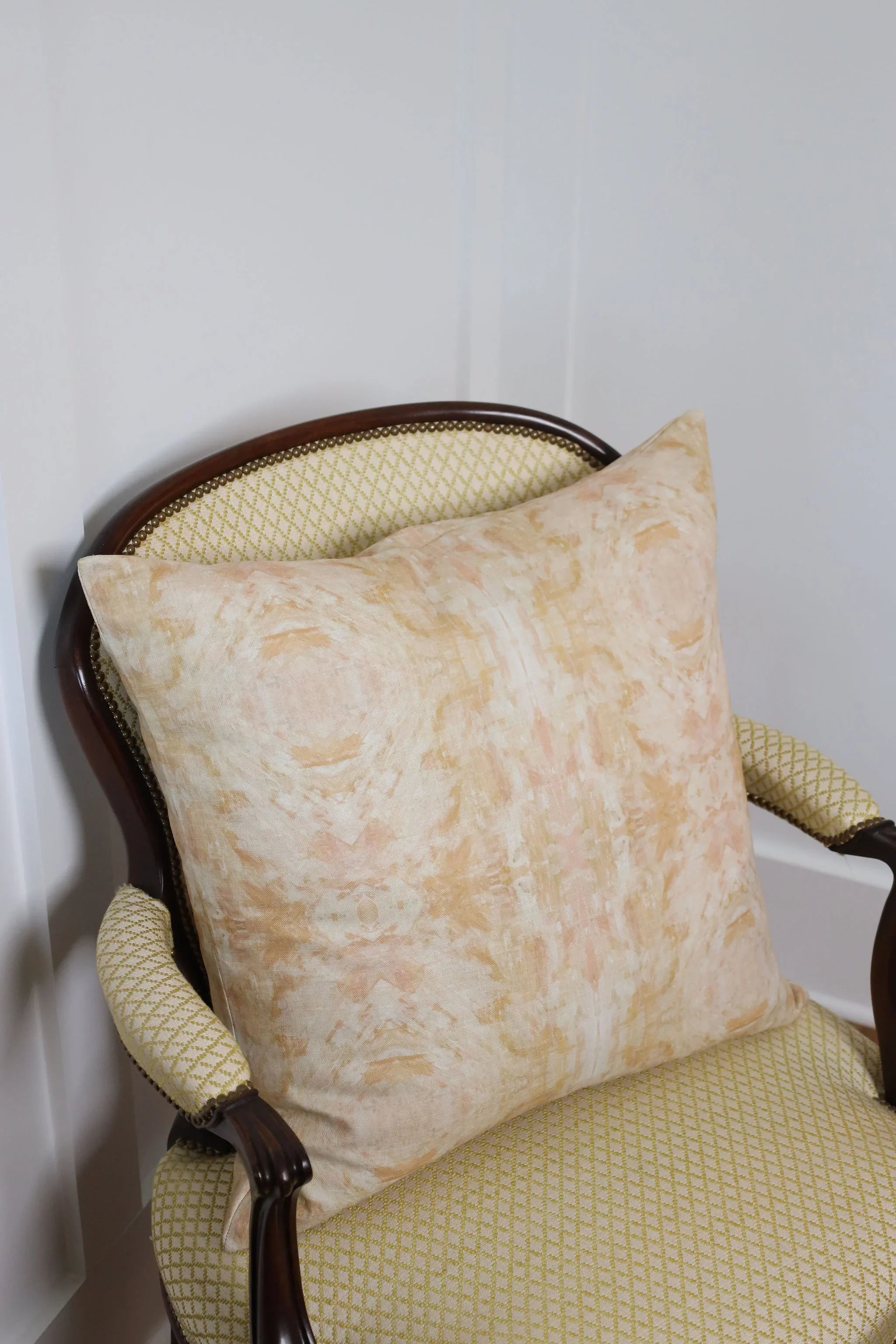 Luxury decorative pillow featuring an abstract topiary-inspired pattern in warm autumn gold and neutral tones, styled for a layered modern traditional interior.